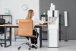 © Pixel-Shot - Businesswoman pouring water from cooler in office, back view