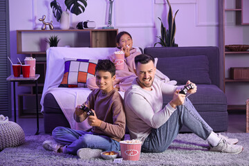 Canvas Print - Father with his children playing video game at home in evening