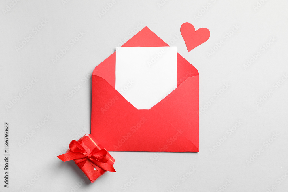 Envelope with blank card, paper heart and gift box on grey background. Valentine's day celebration