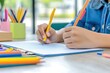 © Espresso - A child's hands holding a yellow pencil and pen, writing in a notebook surrounded by colorful stationery.