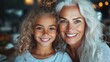 © svastix - An elderly woman with stunning grey hair smiles affectionately with her happy granddaughter, capturing a moment of heartfelt family joy and love in an intimate setting.
