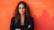 © svastix - A confident woman dressed in black stands against a vivid orange background, symbolizing empowerment and elegance, creating a striking and dynamic visual.