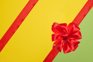 Wall Mural - Tied bow made of red silk ribbon on green yellow background, decor for a gift