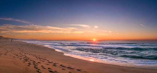 monterey bay sunset with lonely beachcomber footprints. beach stretches forever