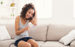 © Prostock-studio - Smiling and excited african-american girl checking her recent pregnancy test, sitting on beige couch at home, copy space