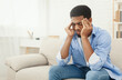 © Prostock-studio - Upset african-american man squeezing head with hands, writhing in pain, suffering from headache at home, copy space