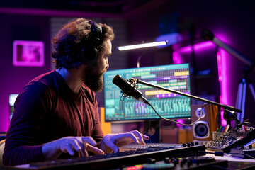 Fototapete - Music producer singing song on microphone and playing piano keyboard to record tunes on aw software interface. Artist creating soundtracks with audio equipment, midi controller gear.