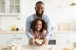 © Prostock-studio - Bonding And Togetherness Concept. Portrait of happy african american dad and daughter baking in the kitchen and holding dough in heart shape in hands, preparing present for mother's day