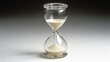 © Sinechana - 81.Crisp image of a minimalist hourglass with fine sand gently falling through its center, set against a bright white backdrop; high-resolution details capture the clarity of the glass and the even