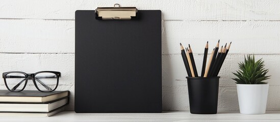 Simple desk setup with A4 paper, glasses, books, and pencil cup next to clipboard.