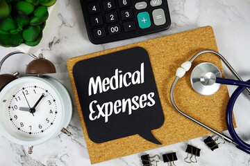 Medical Expenses text on speech bubble with alarm clock, magnifying glass and stethoscope on marble background