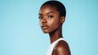 © night - A young woman with short black hair and dark skin wears a white sleeveless top and looks directly at the camera, against a light blue background.
