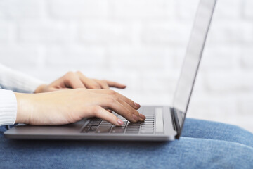 Wall Mural - Close-up image of female hands typing on a cutting-edge laptop keyboard, with a soft blur of an office setting in the backdrop