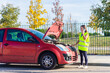 © ADDICTIVE STOCK - Woman in safety vest calling for assistance by broken car