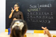 © ADDICTIVE STOCK - Sign language class with teacher and alphabet lesson on chalkboard
