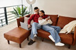 © LIGHTFIELD STUDIOS - A couple in winter attire relaxes together on their couch at home.