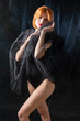 © Mountains Hunter - A young red-haired girl in a black bodysuit poses in the studio against a dark background.