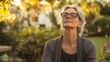© Morning - A woman with grey hair and glasses meditates in nature with her eyes closed.