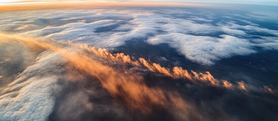 Wall Mural - Aerial view of dramatic clouds illuminated by sunset from an airplane high above the earth's surface