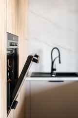 Wall Mural - Modern kitchen interior with black appliances and wooden accents enhancing elegance