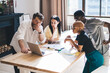 © BullRun - Creative multiracial people seriously looking at laptop at table with drawings