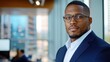 © svastix - A professional man in a suit and glasses stands confidently in a bright, modern office with cityscape windows, conveying leadership and ambition.