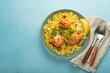 © somegirl - Delicious indian chicken biryani with chicken, garnished with fresh cilantro and lemon, in a bowl on a blue table with copy space. Authentic dish of India