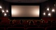 © Josh Zachary - Cinema blank wide screen and people in red chairs in the cinema hall. Blurred People silhouettes watching movie performance.