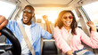 © Prostock-studio - Summer Holidays And Roadtrip Concept. Front view portrait of excited black couple in sunglasses driving car, dancing to music and singing favorite song, going on vacation for rest and relax, sun flare