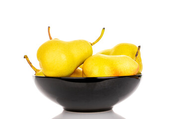 Wall Mural - Several yellow ripe pears in a black ceramic plate, close-up, isolated on a white background.