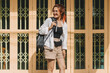 © Suthida - Asian Thai woman carrying backpack, smiling and standing in front of old style door at old town in Thailand on sunny day, happy traveling alone.