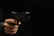 © Rawf8 - Hand holding a gun closeup, armed man on dark background. Danger and crime