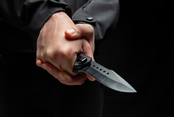 Wall Mural - Criminal holding a knife with both hands closeup, armed attack concept.