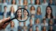 © NoblePix - A hand holding a magnifying glass carefully examines several personal portraits on the wall, representing careful scrutiny or selection. Diversity
