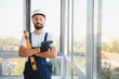 © Serhii - Construction worker repairing plastic window with screwdriver indoors, space for text.