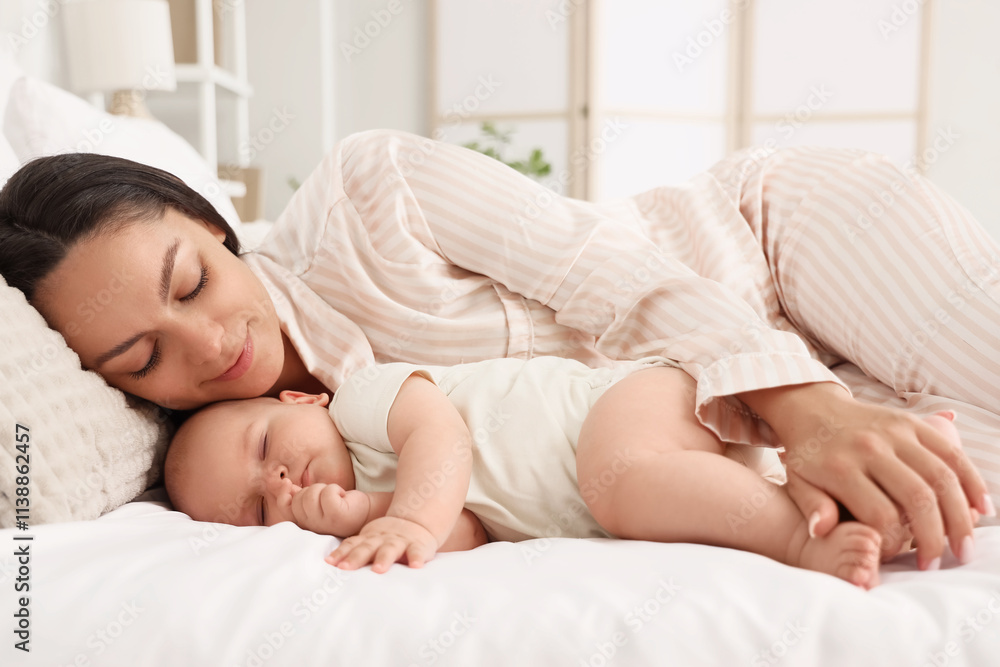 Happy mother with her sleeping baby lying on bed, closeup