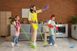 © Pixel-Shot - Mother and her children in headphones having fun while cleaning at home