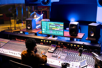 Leinwandbilder - African american audio expert editing tunes with digital software on pc, mixing and mastering tracks with motorized faders and switchers. Professional music producer working on new songs.