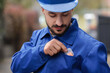 © Pixel-Shot - Male builder taking earplugs from pocket outdoors, closeup