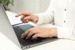 © New Africa - Businesswoman using laptop at white table indoors, closeup. Modern technology