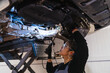 © Koldo_Studio - Female chinese mechanic inspecting car's undercarriage in repair shop