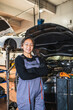 © Koldo_Studio - Young chinese female mechanic smiling with arms crossed in auto repair shop