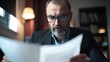 © milenialdesastudio - Concerned man reading document in dim light.