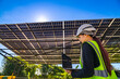 © ultramansk - Engineer in safety vest and helmet pointing towards a solar powered carport, illustrating eco-friendly innovation in parking infrastructure. Solar panels provide shade and sustainable energy.