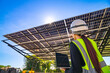 © ultramansk - Engineer in safety vest and helmet pointing towards a solar powered carport, illustrating eco-friendly innovation in parking infrastructure. Solar panels provide shade and sustainable energy.