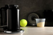 © Atlas - Black plastic jars and bottle, measuring cup and sport equipment on dark gray background, space for text
