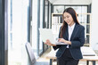 © SOMKID - Asian businesswoman working on digital laptop standing in office, Businesswoman and Marketing concept.