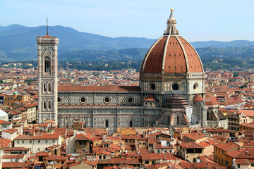 Aerial view of the historic part of the city of Florence (Italy) with the Cathedral Cattedrale di Santa Maria del Fiore against the background of the green hills