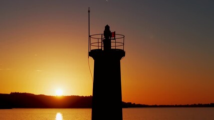 Wall Mural - Silhouetted Lighthouse During Golden Sunset - aerial shot