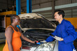 © Verin - mechanic explaining a car problem to africa woman client during examination,concept for business garage service,auto service